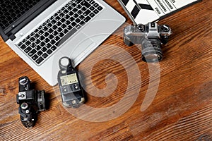 Top view closeup of cameras, notebook, photometer, and a movie clapperboard on a wooden table photo