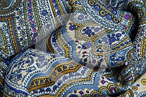 Top view closeup on crumpled soft cotton scarf with bright oriental ornament