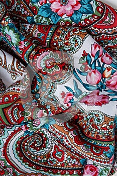 top view closeup on crumpled white cotton scarf with colorful floral ornament