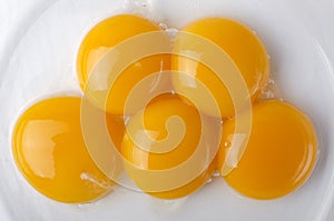 Top view and closeup of five separated yolk eggs in the bowl as a background