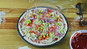 Top view closeup man by hands put tomatoes slices on raw pizza with many ingredients