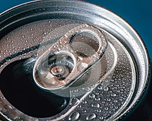 Top view closeup of an opened metal drinks can with water drops on a blue background