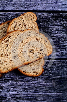 Top view closeup of a sliced loaf of brown bread on a wooden table