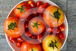 Top view closeup studio shot of two healthy fresh delicious red and cherry tomatoes vegetable species in white plastic bowl