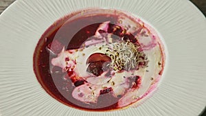 Top view closeup traditional red borscht decorated with sour cream and wheat sprouts