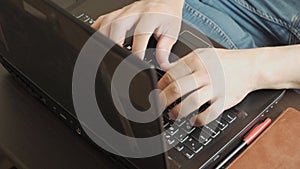 Top view. Closeup unrecognisable guy's a freelancer working on laptop at home. Man hands typing on notebook keyboard.