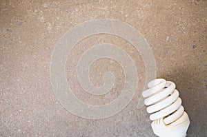 Top view closeup of a white spiral light bulb on a toned rough stone textured surface
