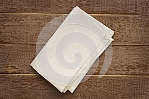 Top view of cloth napkins of beige, color on rustic brown wooden table