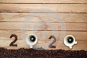 Top view of coffee beans and hot fresh coffee in a white cup with foam and text number design 2024 for Happy New Year Concept. on