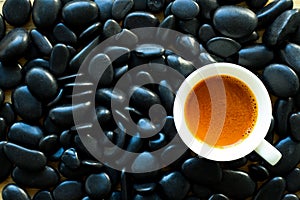 Top view of coffee cup on black stones.