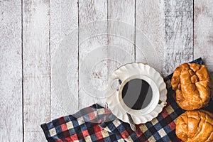 Top view of Coffee cup with bread and tablecloth on wooden table background.