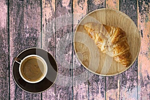 Top view of coffee cup and croissant on wooden table background