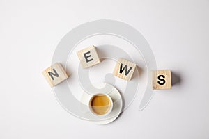 top view of coffee cup and wooden alphabet cubes making word news, on white background