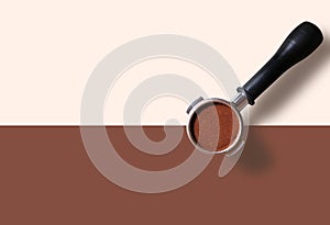 Top view of Coffee Machine Portafilter Filled with Ground Coffee Beans on two tone color background