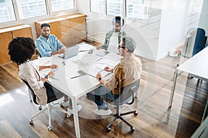 Top view of collaborative meeting shows diverse team engaging in strategic discussion at an office table