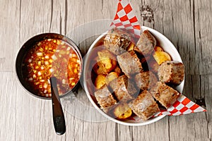 Top view of colombian morcilla blood sausage and a bowl of vegetable soup on a wooden table
