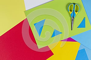 Top view of colored paper with colorful scissors. Kids art and craft paper applique background