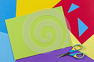Top view of colored paper with colorful scissors. Kids art and craft paper applique background