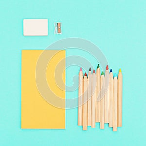 Top view of colored pencils and yellow color sketch pad for creativity. Set of wooden multicolored pencils