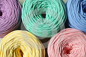 Top view of colorful blue, pink, yellow, lilac, minty bobbins of t-shirt yarn for hand knitting