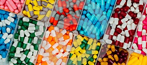Top view of colorful capsule pills in  plastic box. Antibiotic drugs, painkiller medicine, vitamins, and supplements capsule pills