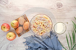 top view of colorful cereal corn flakes, apple , egg and milk on table
