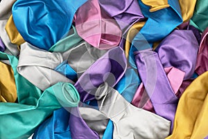 Top view of colorful deflated balloons texture background. Pile of multiple colorful unblown balloons pattern. Heap of colorful