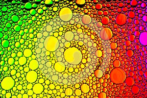 Top view on a colorful drops of oil on the water. Rainbow or spectrum colored circles, ovals