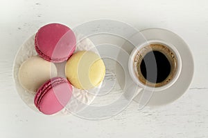 Top view colorful macaroons and cup of coffee on wooden table