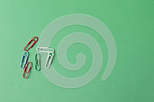 Top view of colorful paperclips over green background