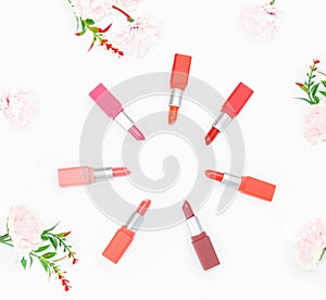 Top view colorful pastel lipstick arranged  in a circle on white background and pink carnation flower white copy space,selective