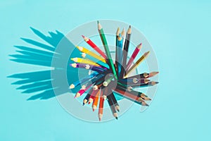 Top view of colorful pencil in glass with long shadow on pastel background