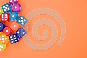 Top view of colorful plastic dice against an orange background with space for text