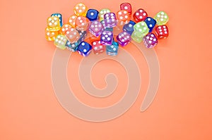 Top view of colorful plastic dice against an orange background with space for text