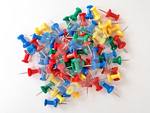 Top view of colorful plastic push pins on white paper background