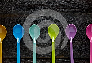 Top view colorful plastic spoon on wood table background with co