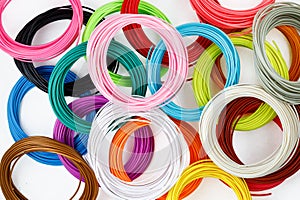 Top view of colorful rolled filament for 3D pen isolated on white. Closeup of plastic bright wires for 3D printer lying on table