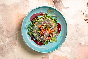 top view colorful salad with pumpkin, lettuce, tomatoes, and quinoa on a blue plate