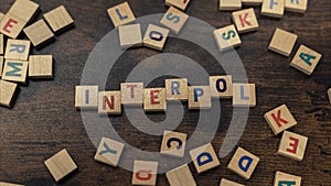 Top view of colorful square wooden letters creating the word INTERPOL. The International Criminal Police Organization