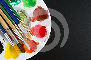 Top view of Colorful Watercolor palette and paintbrush  on a black background and copy space