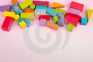 Top view of colorful wooden bricks on the table. Early learning. Educational toys on a pink background