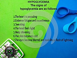 Top view compass and calculator with text the signs of hypoglycemia on a colorful background