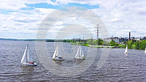 Top view of competition of sailing yachts. Video. Beautiful regattas floating on background of green coast and distant