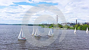 Top view of competition of sailing yachts. Video. Beautiful regattas floating on background of green coast and distant