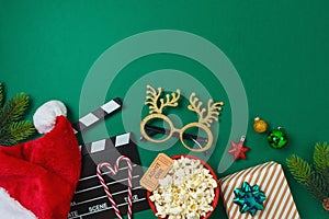 Top view composition for Christmas movie night and party concept with popcorn, Santa hat, decorations and movie clapper board on