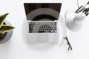 Top view of composition with laptop on white tabletop with glasses, desklamp photo