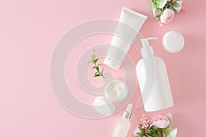 Top view composition made of cosmetic tubes without label, dropper bottle and spring flowers