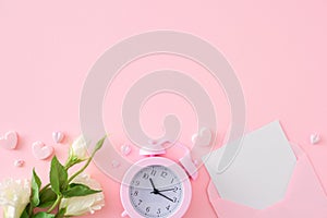 Top view composition made of open envelope with white card, flowers, alarm clock and hearts