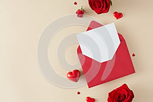 Top view composition made of red roses, hearts and open red envelope with white card