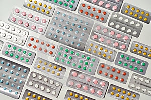Top view of composition with many medical pills, tablets pack in blister lying in orderly manner over white background